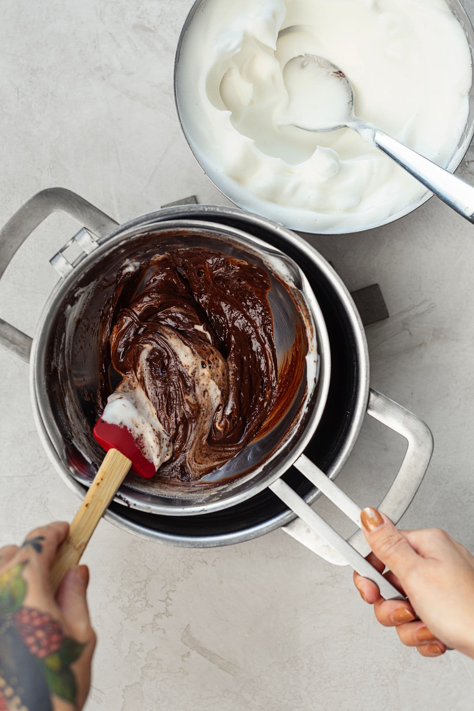 Whipped aquafaba being gently folded into melted chocolate to create a light mousse.