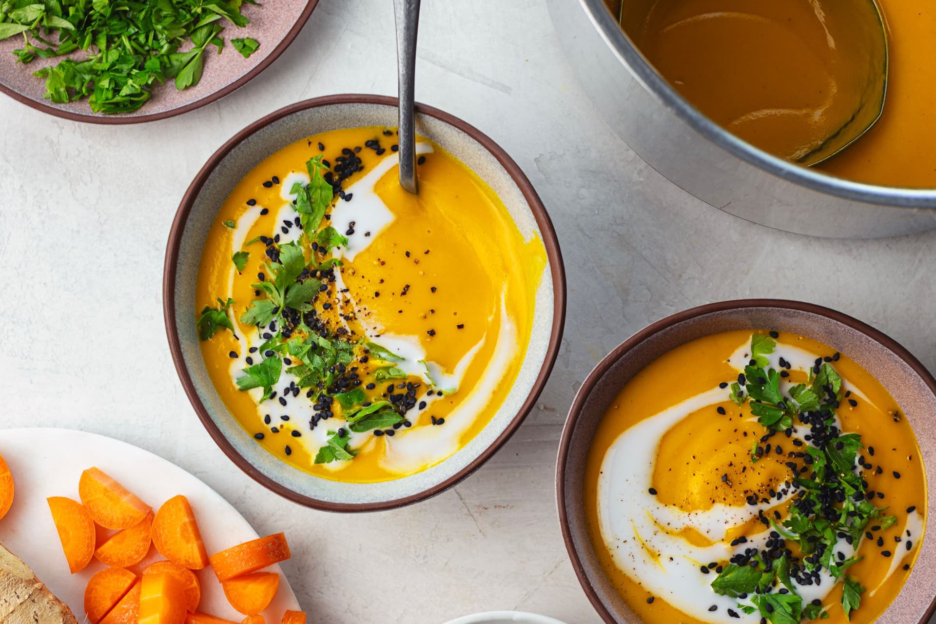Warm bowl of soup with a spoon dipped in, showing the thick and creamy consistency of the carrot purée.