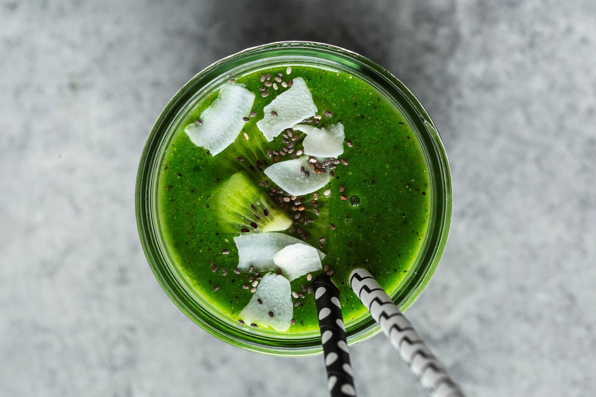 Smoothie verde vibrante servido em frasco de vidro com kiwi, coco e sementes de chia