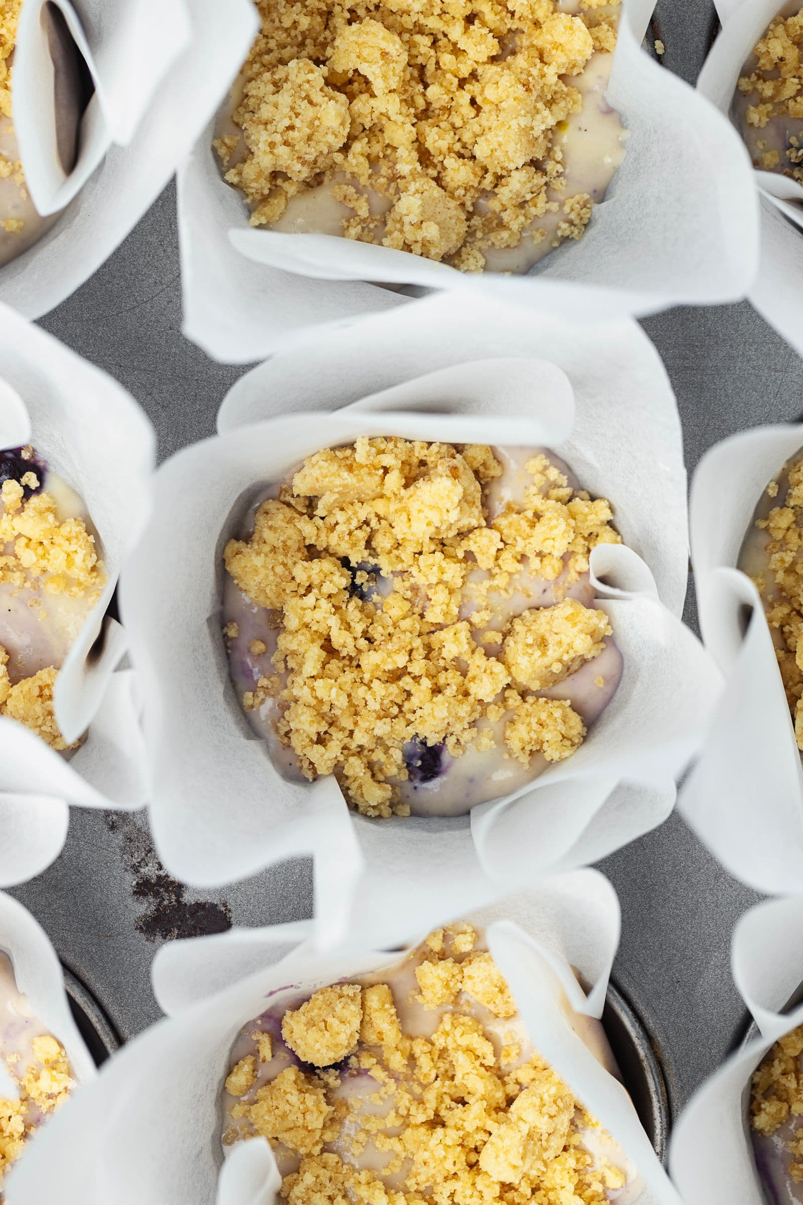 Unbaked lemon blueberry muffins topped with streusel before going into the oven.