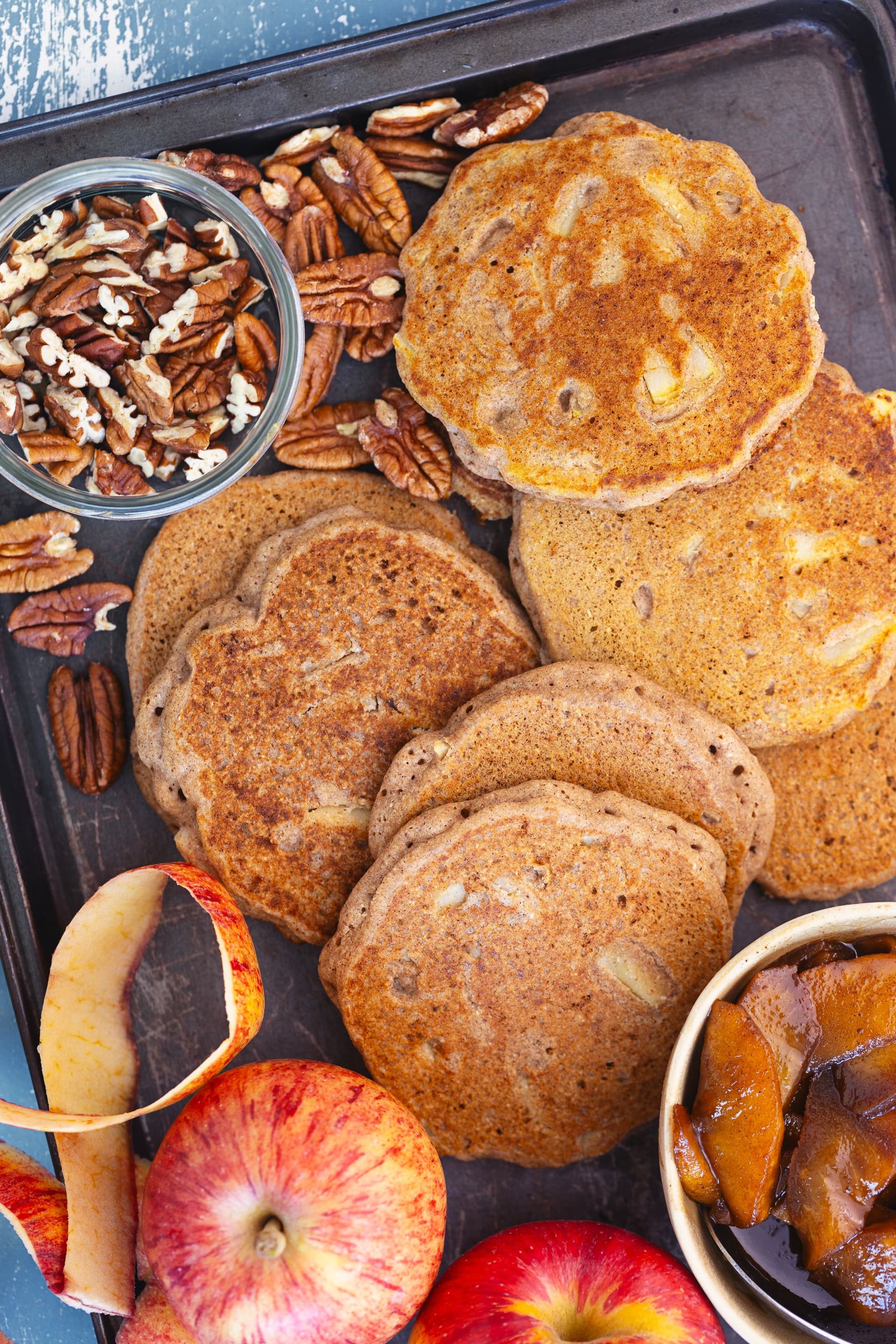 Tray of cooked buckwheat pancakes with pecans, caramel apples and fresh apples.