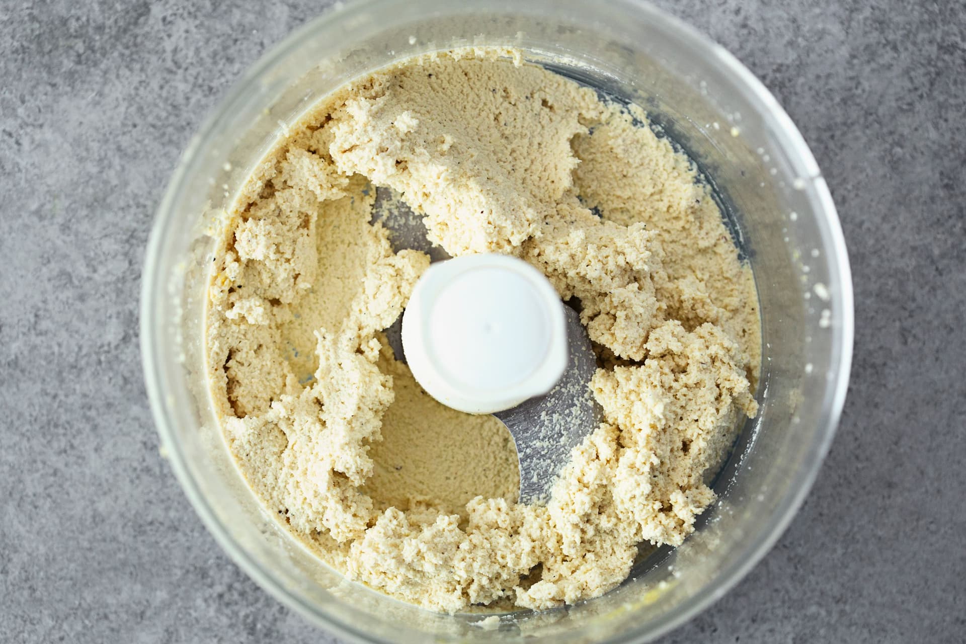 Blended cashew cheese mixture in a food processor bowl, ready to be shaped into a log.
