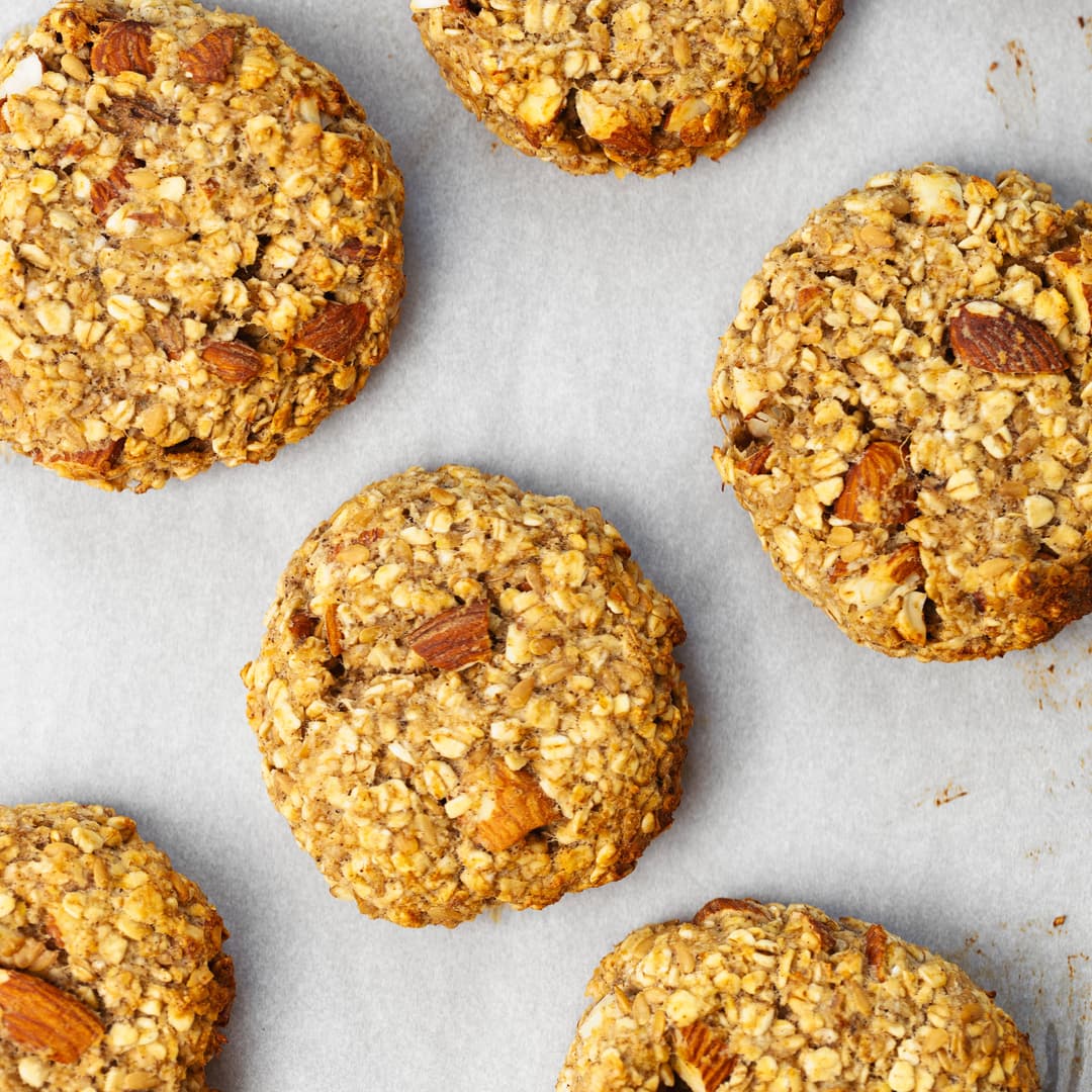 Banana oat cookies with chopped almonds, baked until golden and arranged on a sheet of parchment paper.