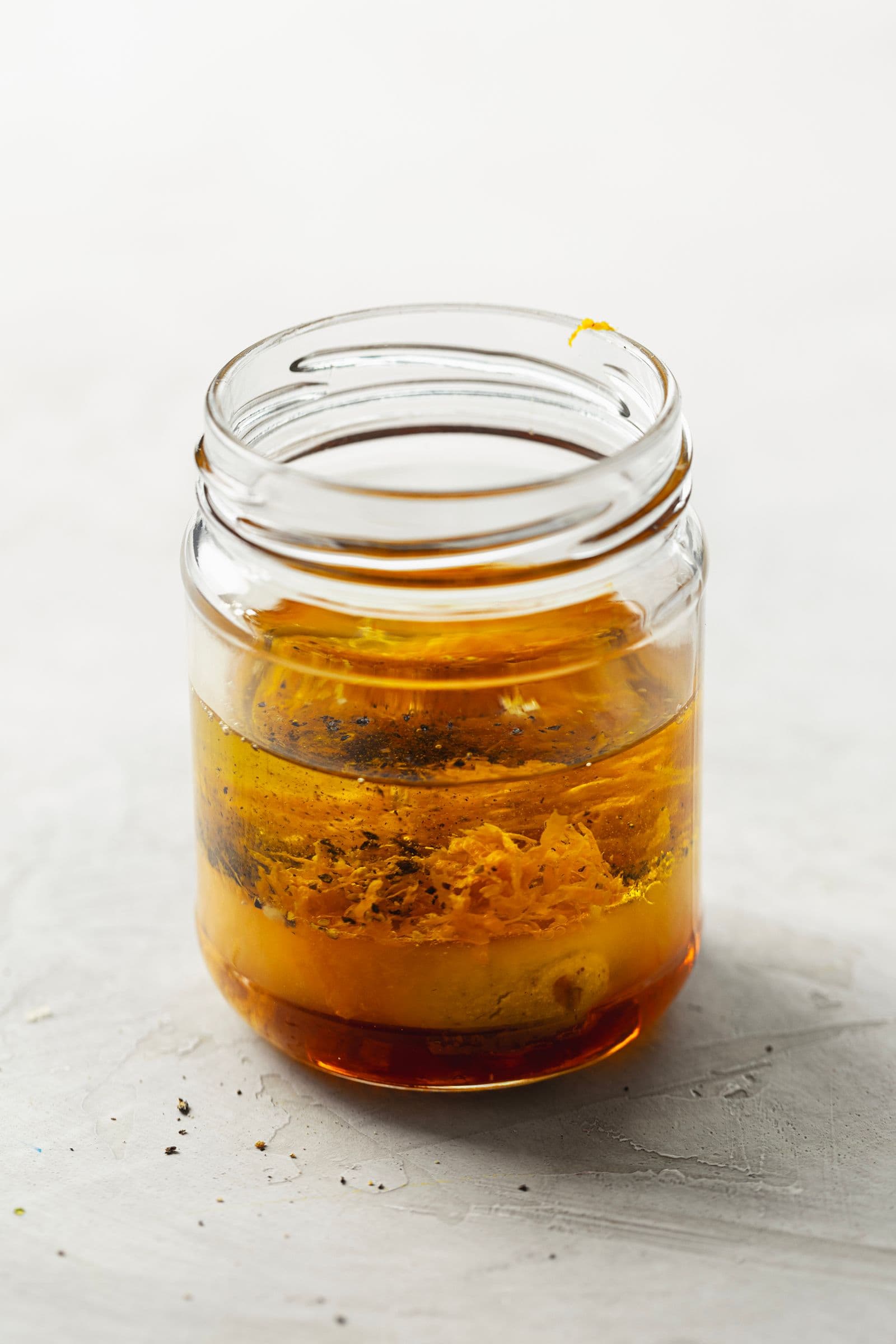 Vinagrete de laranja, mostarda e azeite num frasco de vidro antes de ser agitado.