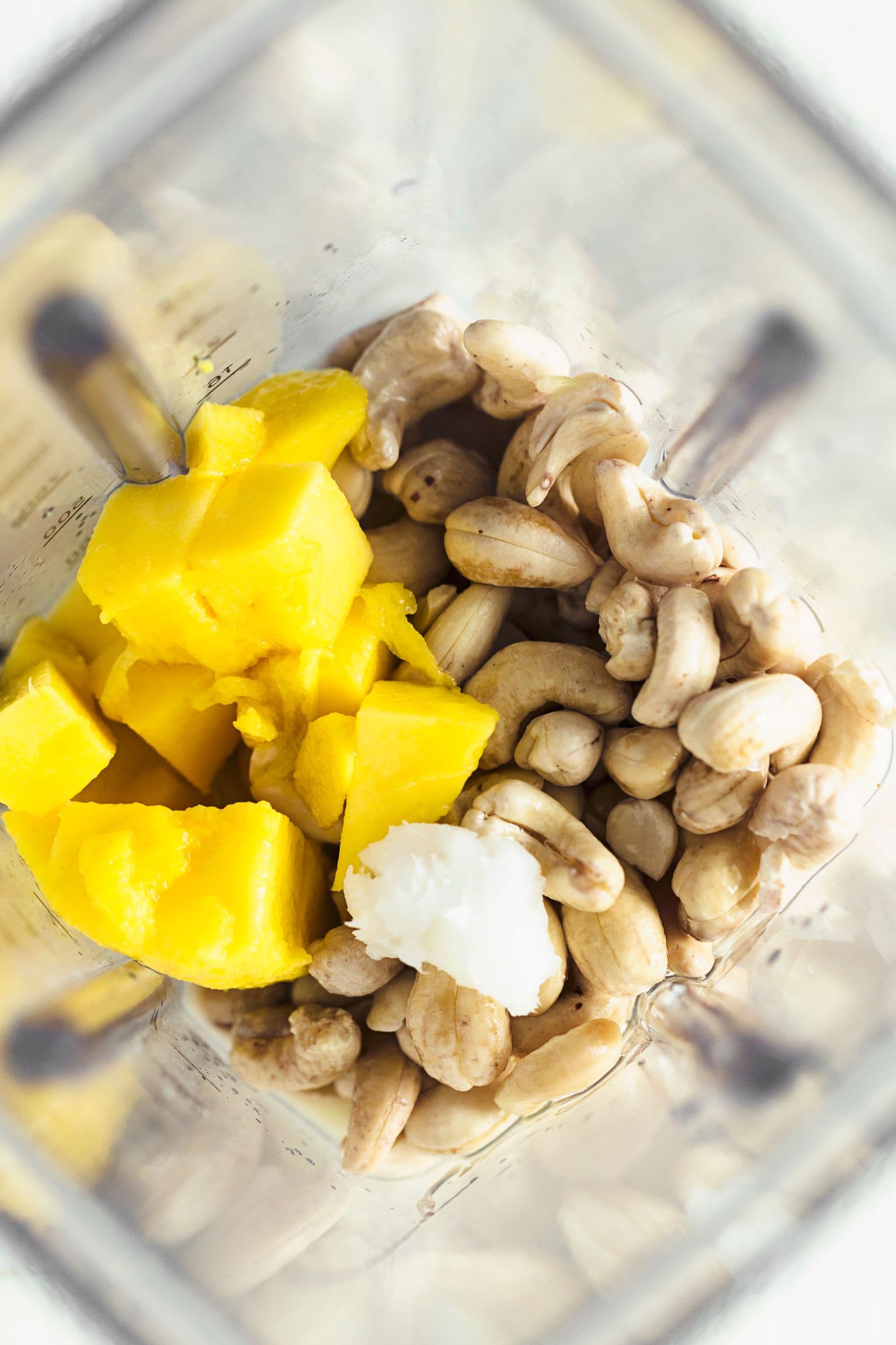 Mango chunks, soaked cashews and coconut oil placed in a blender jug.