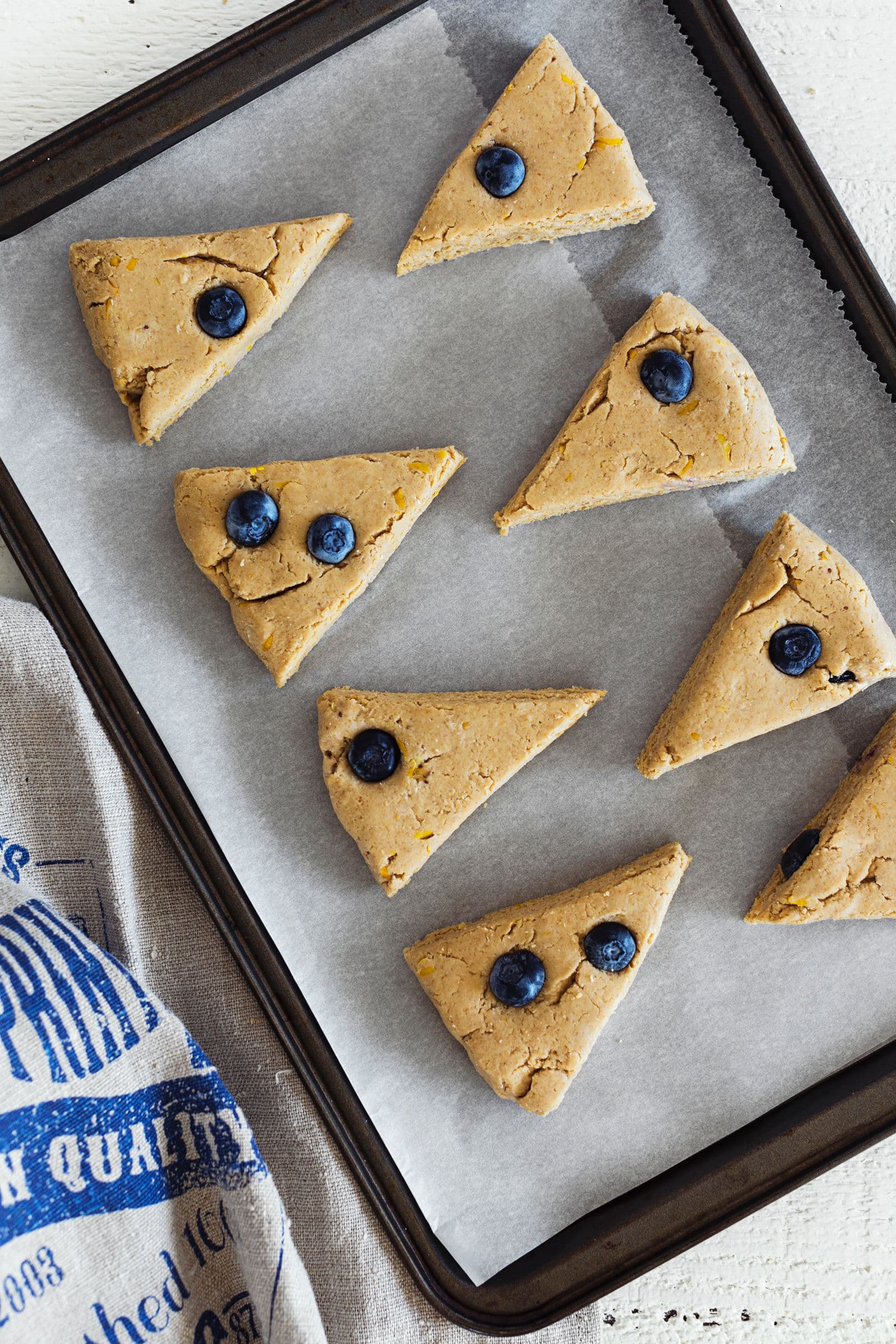 Vegan lemon scone dough sliced into triangular wedges, ready to bake.