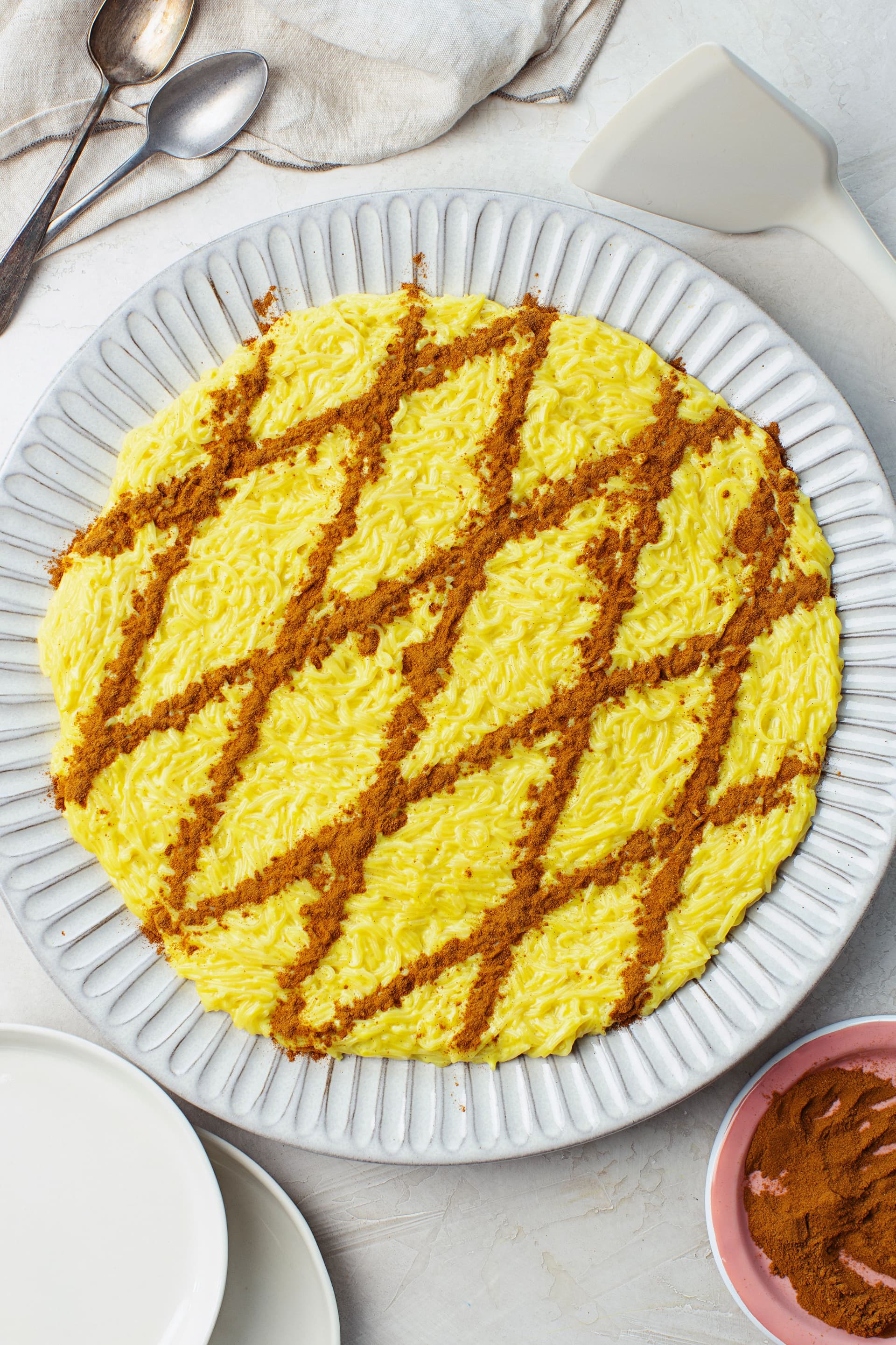 Overhead view of a large plate of vegan Aletria, a creamy Portuguese Christmas dessert topped with a cinnamon lattice pattern.