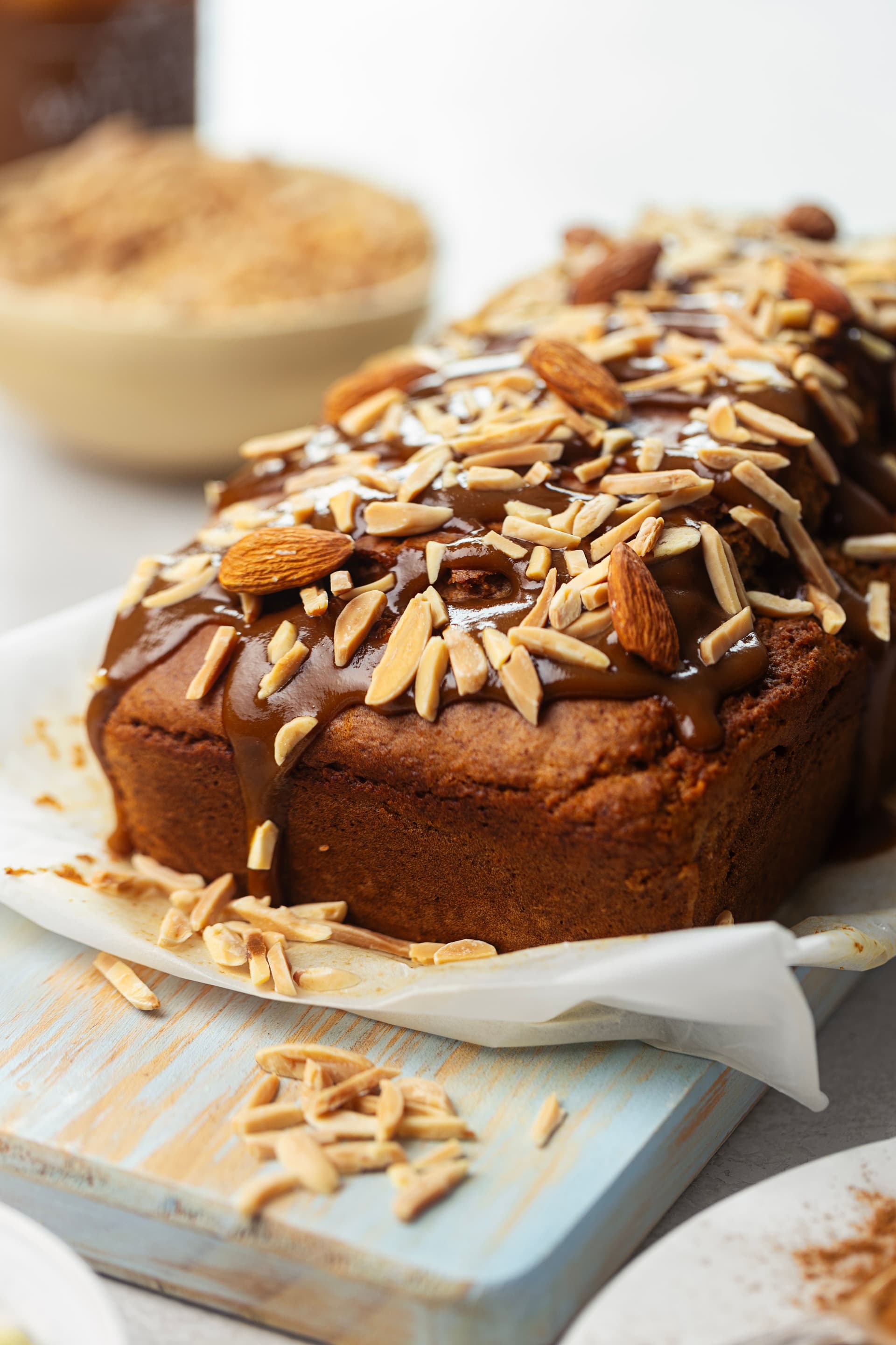 Vegan almond cake drizzled with coconut caramel and topped with slivered and whole almonds, seen up close.