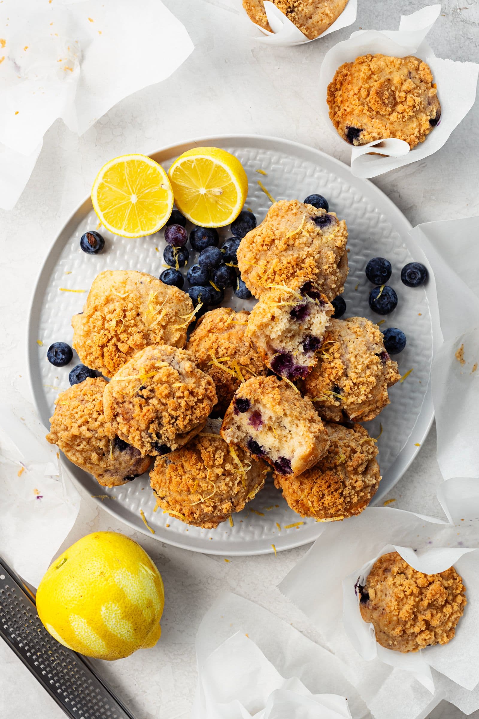 Plate of lemon and blueberry streusel muffins garnished with fresh blueberries and lemon halves.