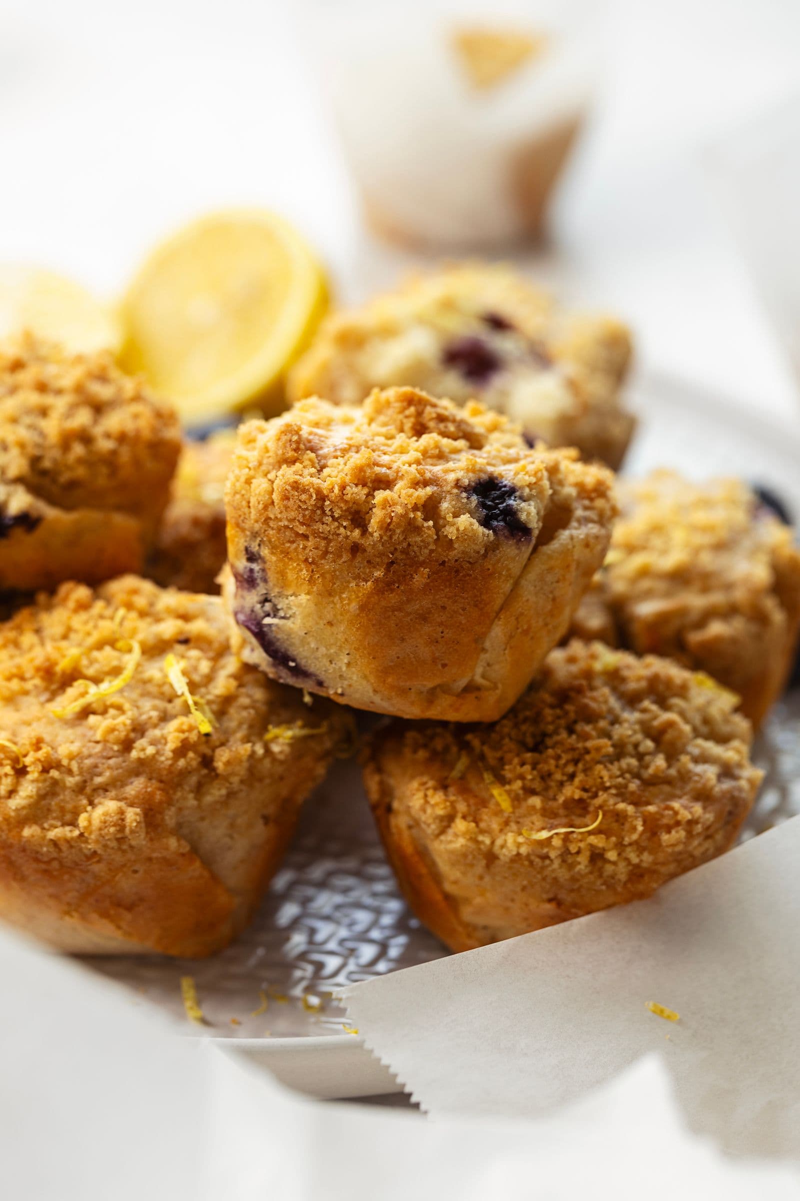 Stacked lemon and blueberry streusel muffins on a plate, with a soft focus background.