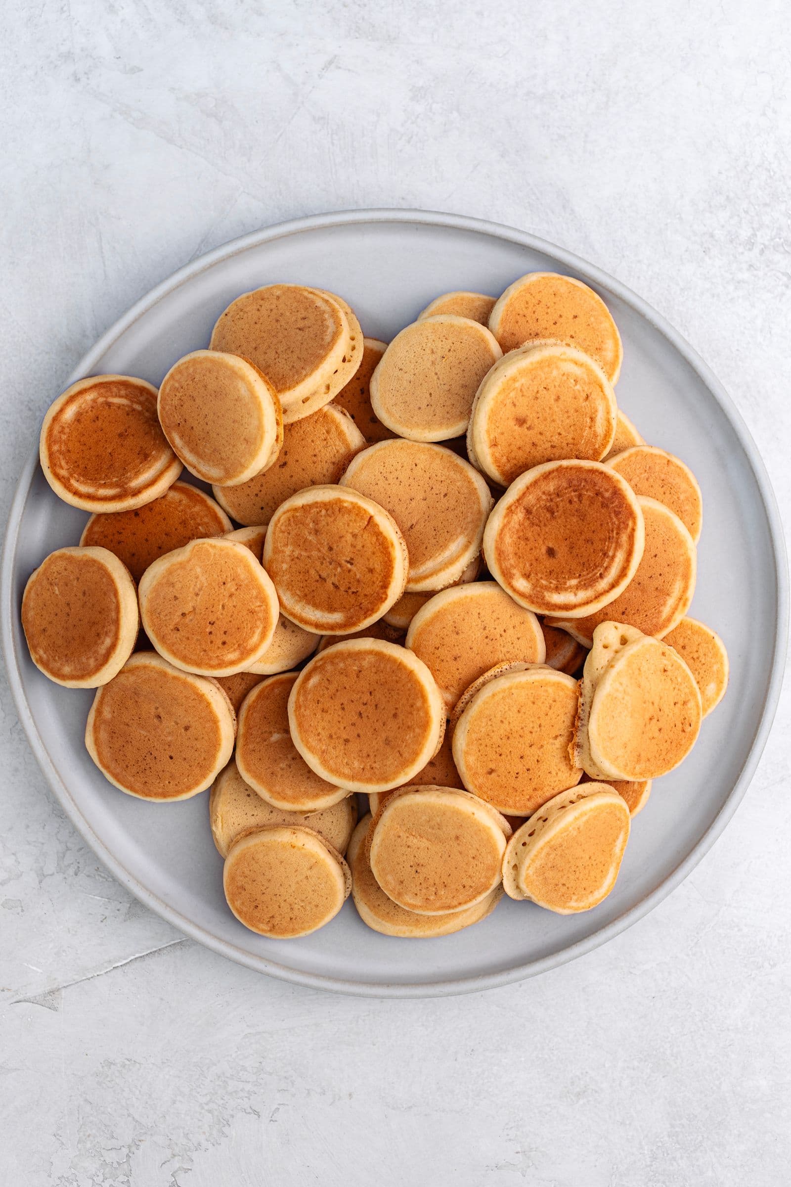 A large plate filled with golden mini vegan pancakes, ready to serve