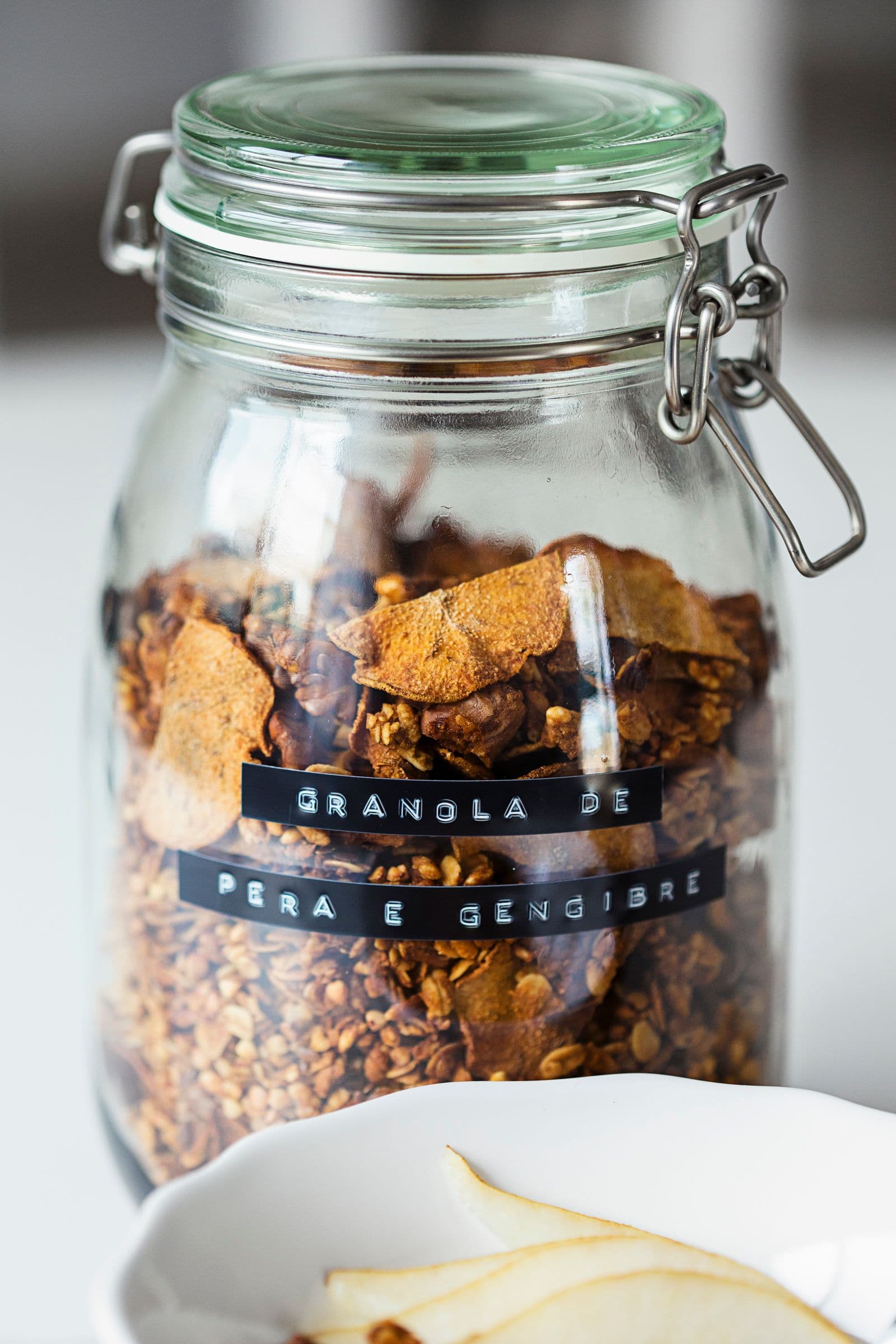 Close-up of a glass jar filled with granola and labelled “Pear & Ginger Granola”.