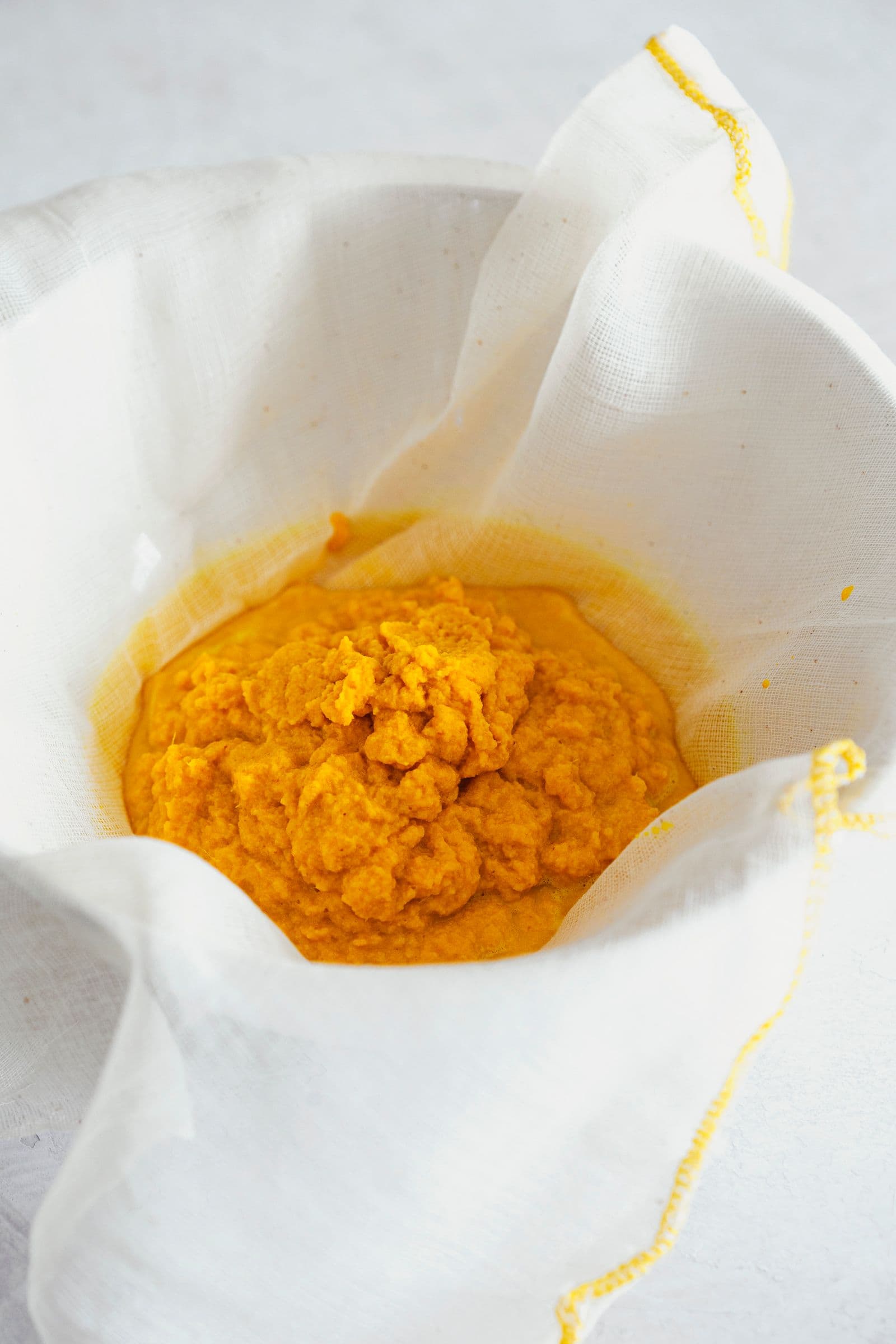 A cloth strainer holding the blended ginger-turmeric pulp before squeezing.