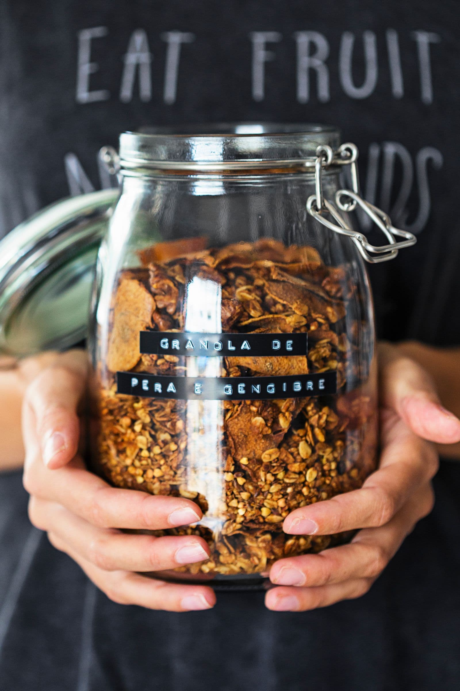 Person holding a labelled jar of pear and ginger granola.
