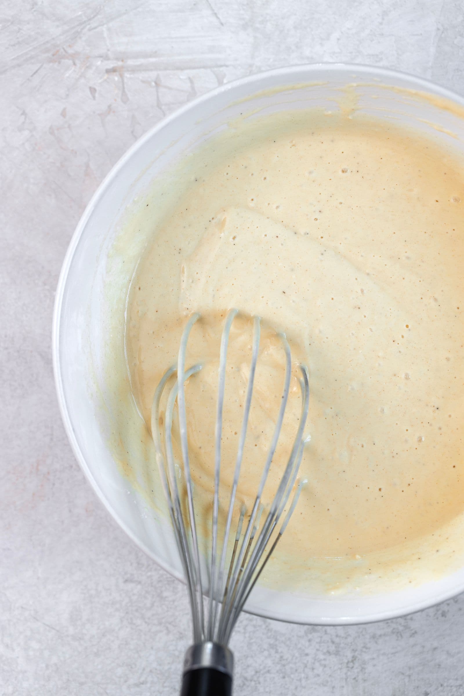 Vegan pancake batter in a mixing bowl with a whisk resting inside, ready to rest before cooking