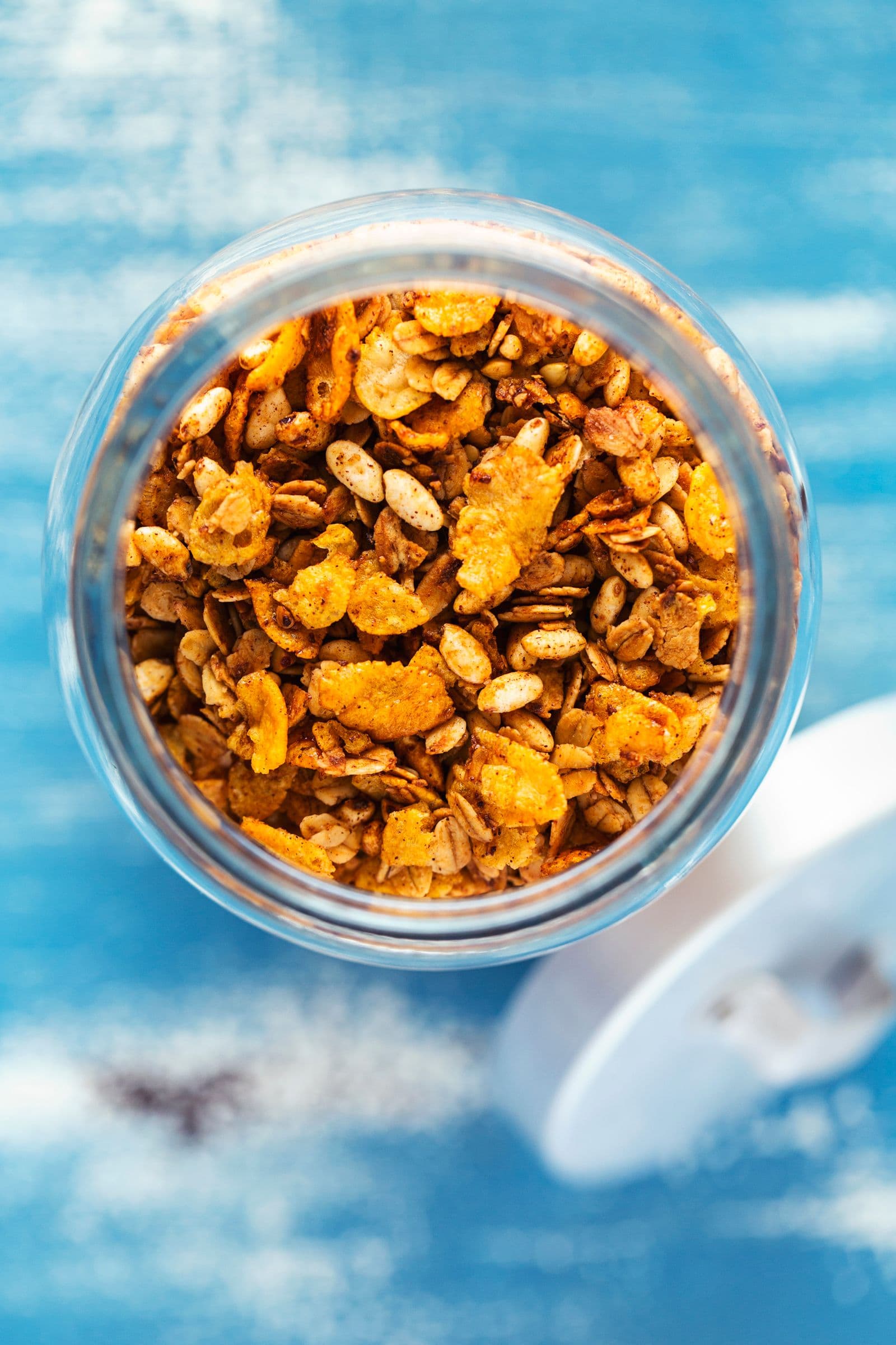 Top view of crunchy cornflake granola inside an open glass jar.