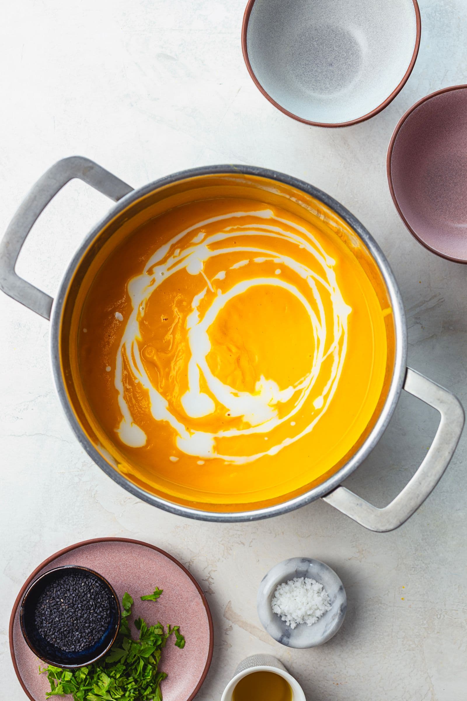 Blended carrot soup, smooth and velvety, finished with a swirl of coconut milk creating a marbled effect on top.