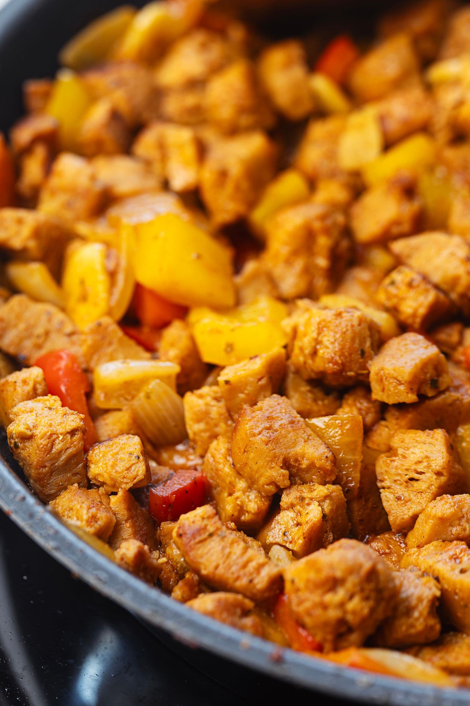 Soy chunks sautéed with yellow and red bell peppers in a skillet, mid-cook in the soy pica pau recipe