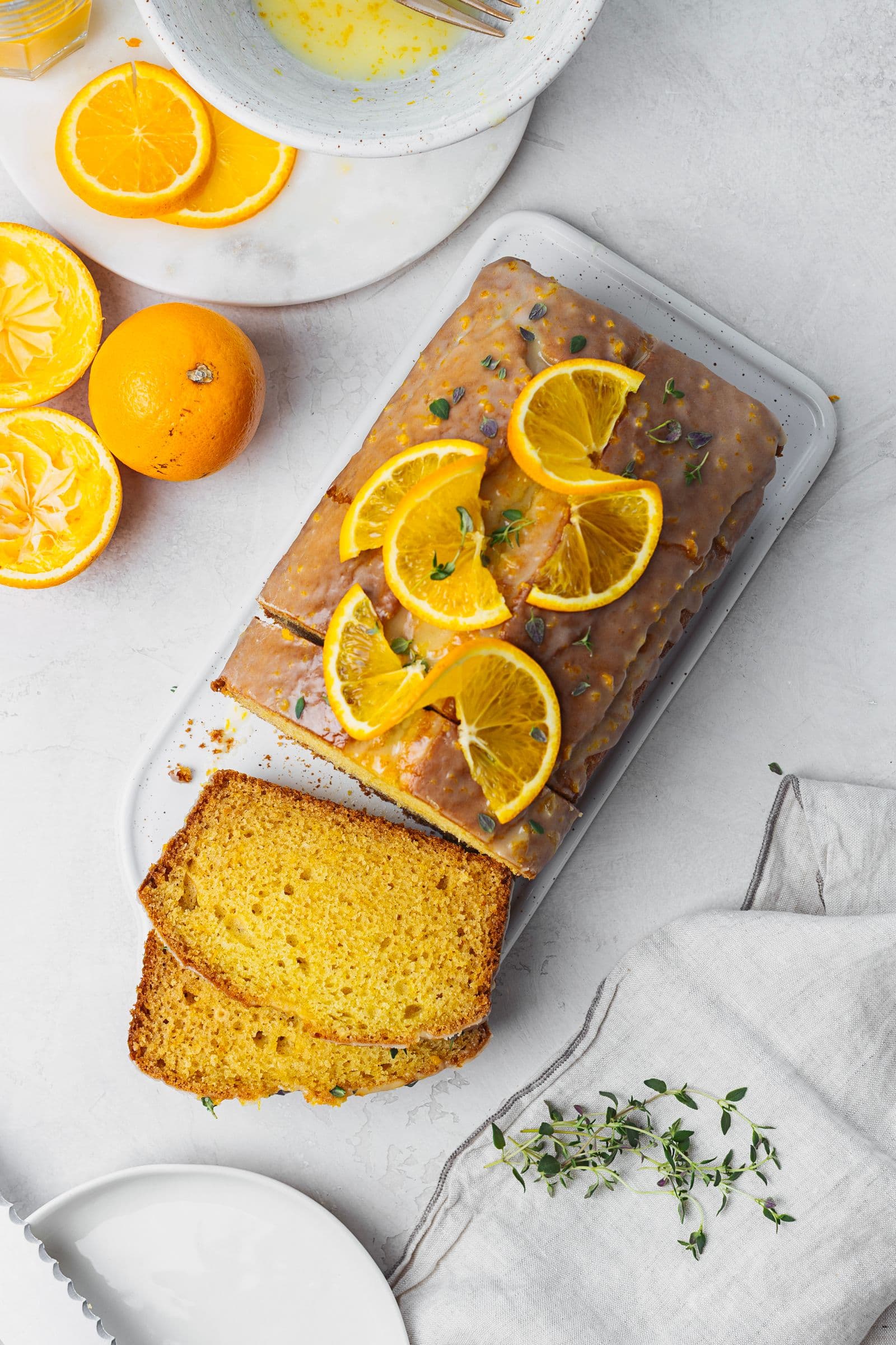 Top view of sliced orange cake with glossy glaze and fresh oranges around.