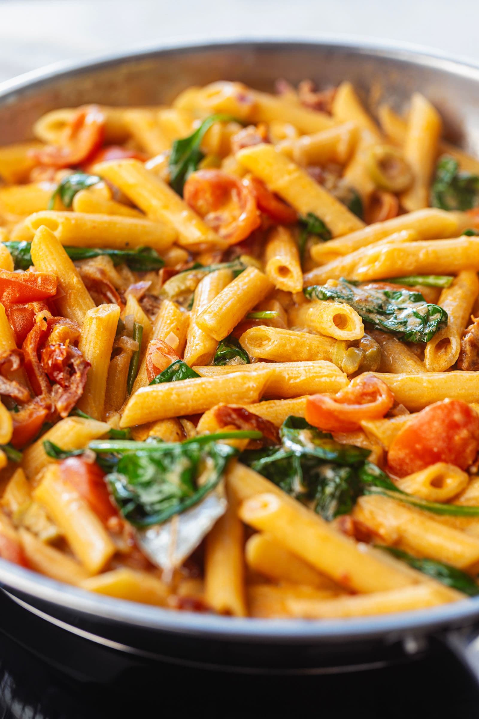One pot creamy tomato and spinach penne in a large pan, showing the rich orange sauce coating the pasta