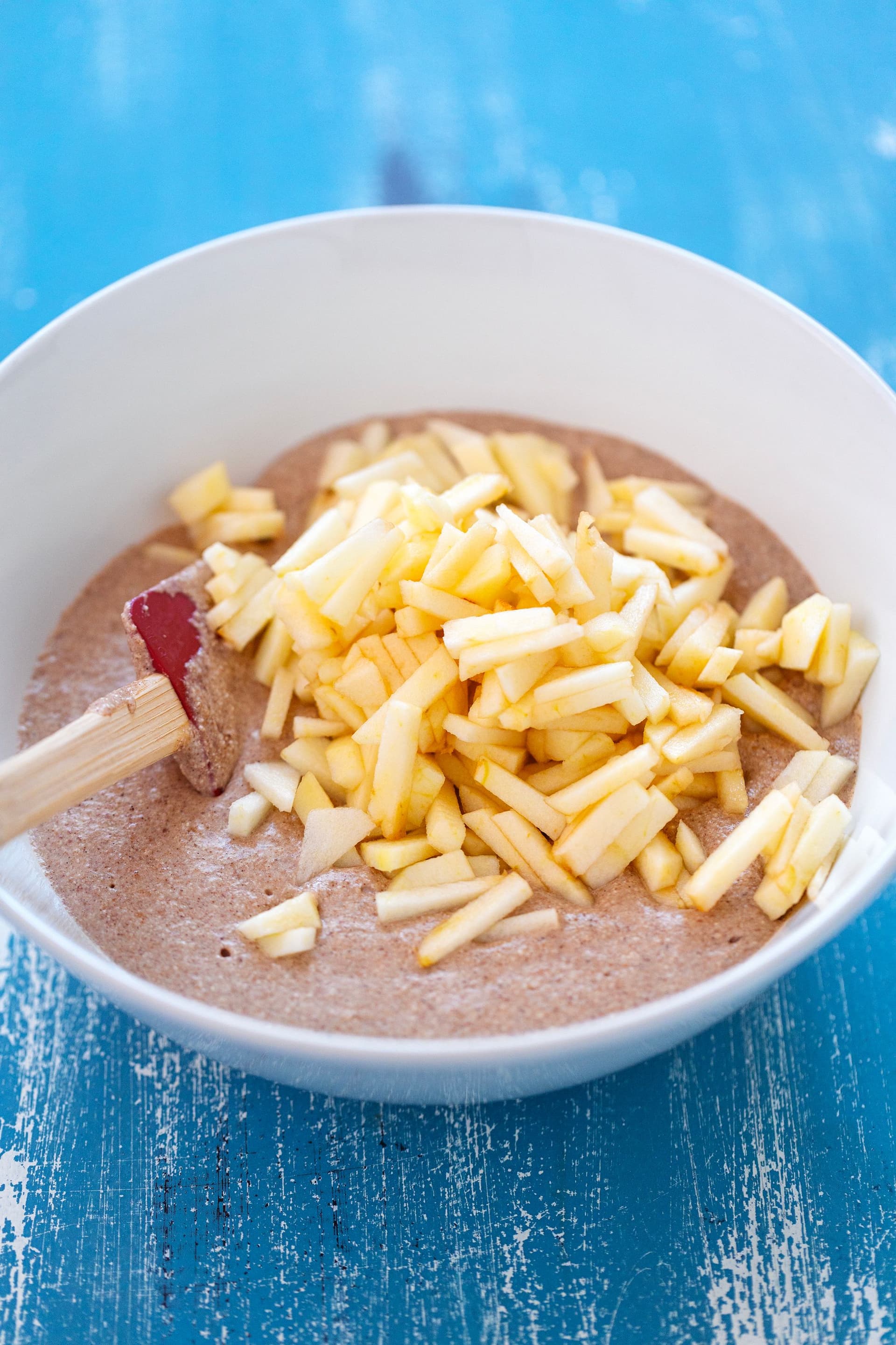 Pancake batter in a bowl with freshly chopped apple ready to be mixed in.